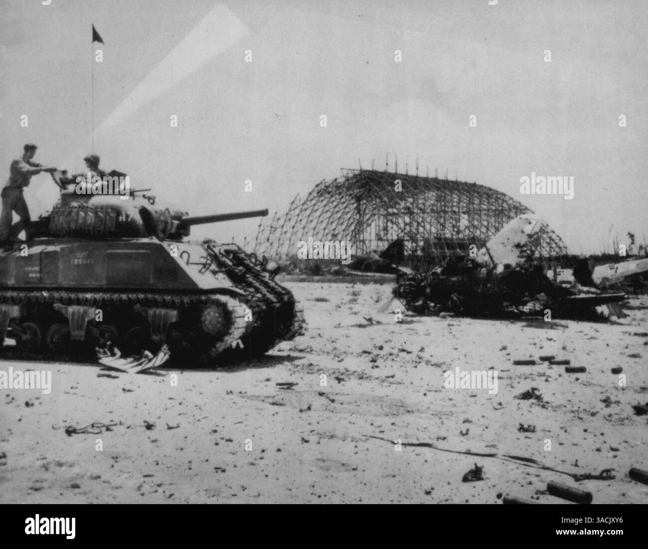 Marines Survey Damage to Peleliu Airfield -- tre Marines statunitensi rilevano i danni alle installazioni nemiche sul campo di aviazione sull'isola di Pelelieu nel gruppo Palau, provocati da bombardamenti navali e aerei pre-invasione, mentre prendono posizione nel loro carro armato sullo sfondo di aerei Jap e un manager. 25 settembre 1944. (Foto di Associated Press Photo). Foto Stock
