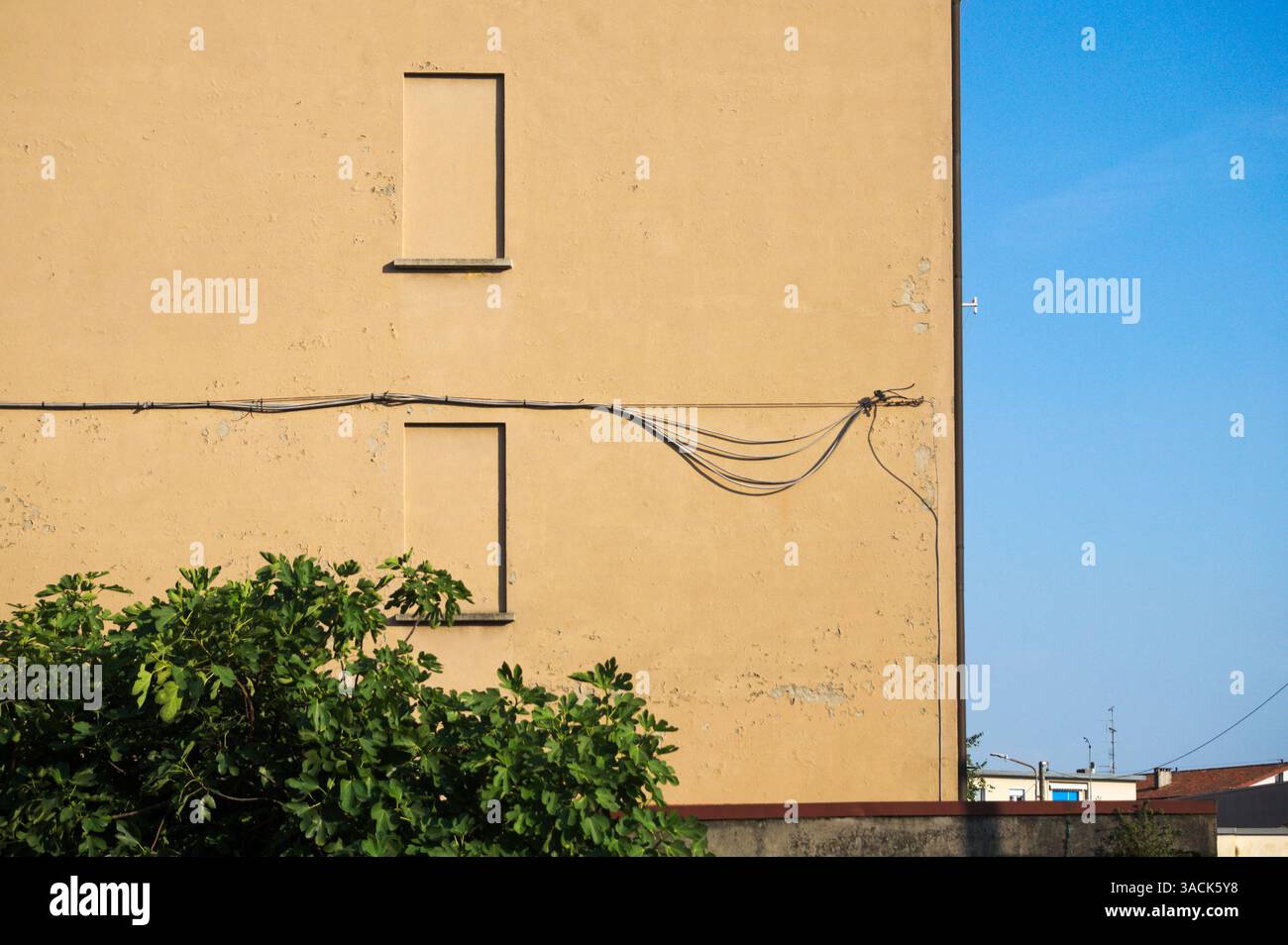 finte finestre su un vecchio edificio residenziale con cavi elettrici attaccati alla parete Foto Stock