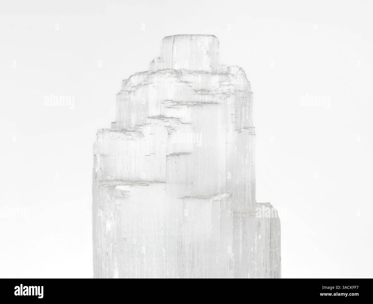 Primo piano del cristallo di selenite su sfondo grigio. Chakra guarigione e mediazione roccia o gemma. Proprietà tranquille, calmanti e di chiarezza mentale per le spiri Foto Stock