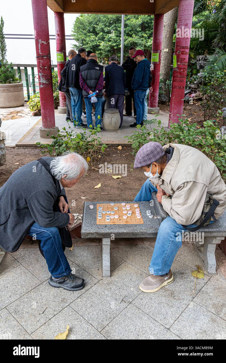 Uomini che giocano a scacchi cinesi (xiangqi) guardati dagli spettatori nella Public Square Street Rest Garden, Nathan Road, Kowloon, Hong Kong, Cina Foto Stock