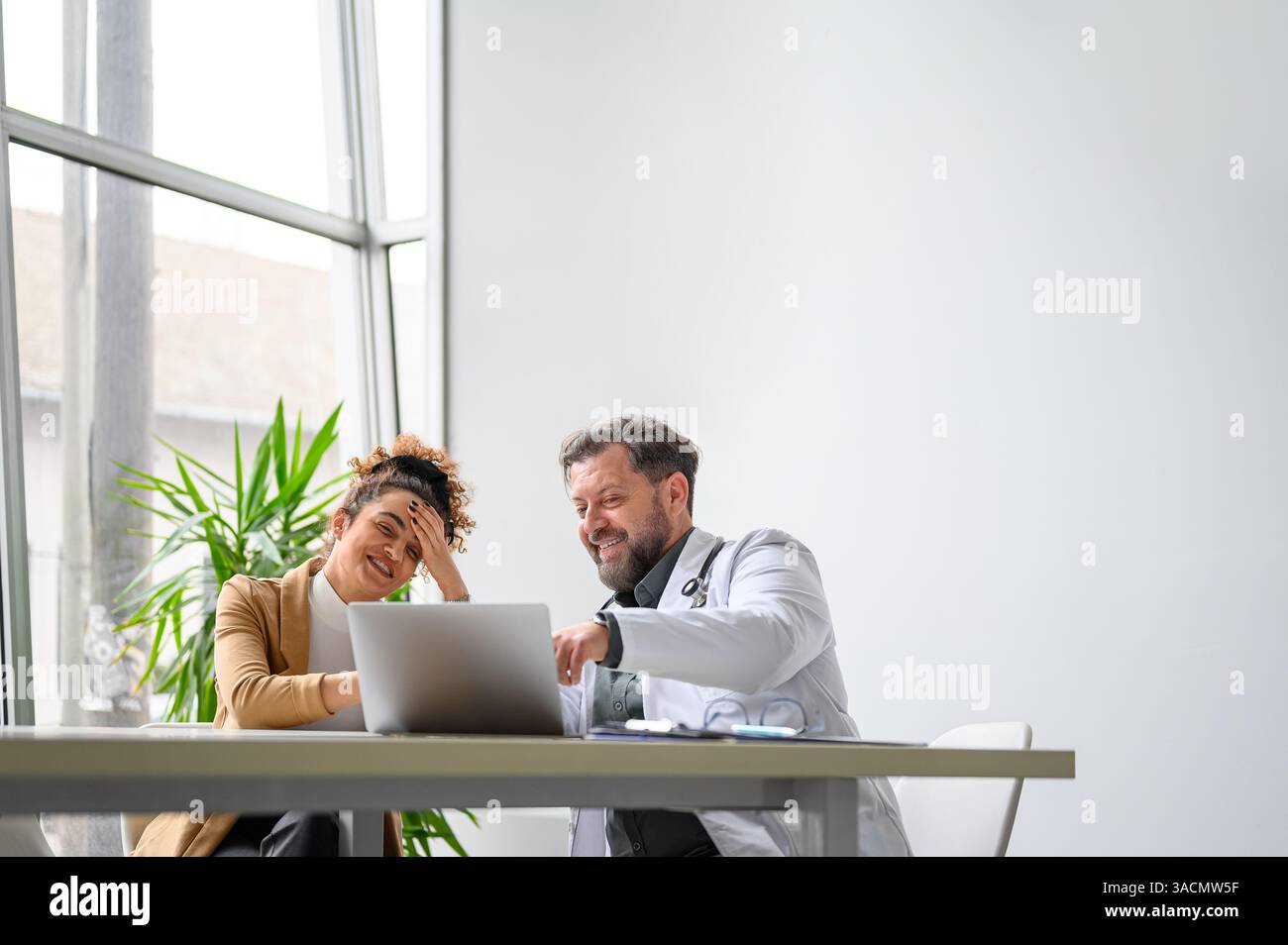 Professionista medico maschile che mostra buone notizie su recenti test medici per paziente femminile in clinica Foto Stock