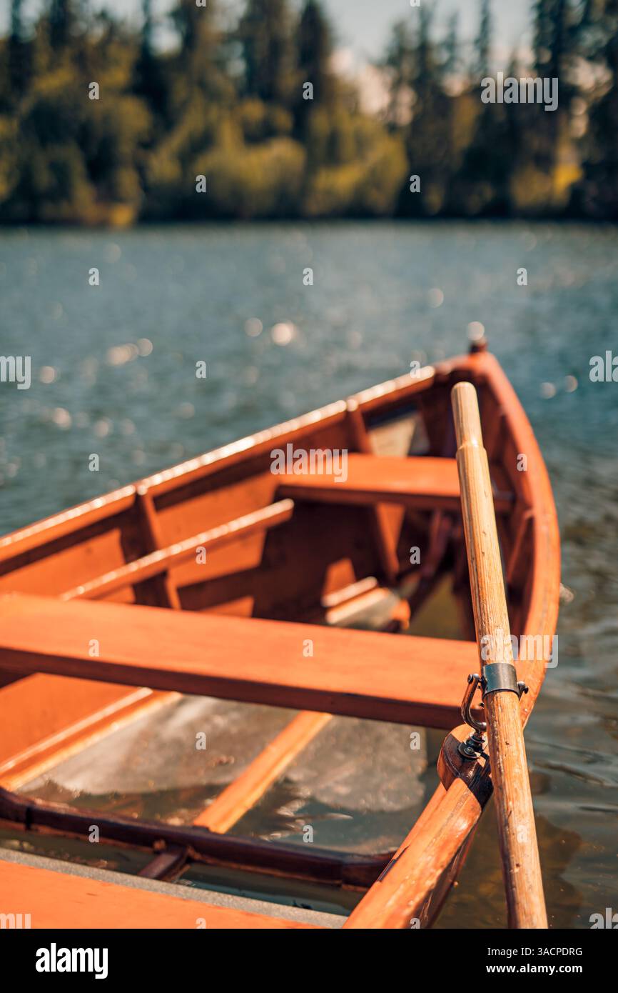 Primo piano del lago autunnale con barche di legno rosse che galleggiano su acque calme, effetto sfocato, circondato da verde pineta, tranquillo paesaggio stagionale Foto Stock
