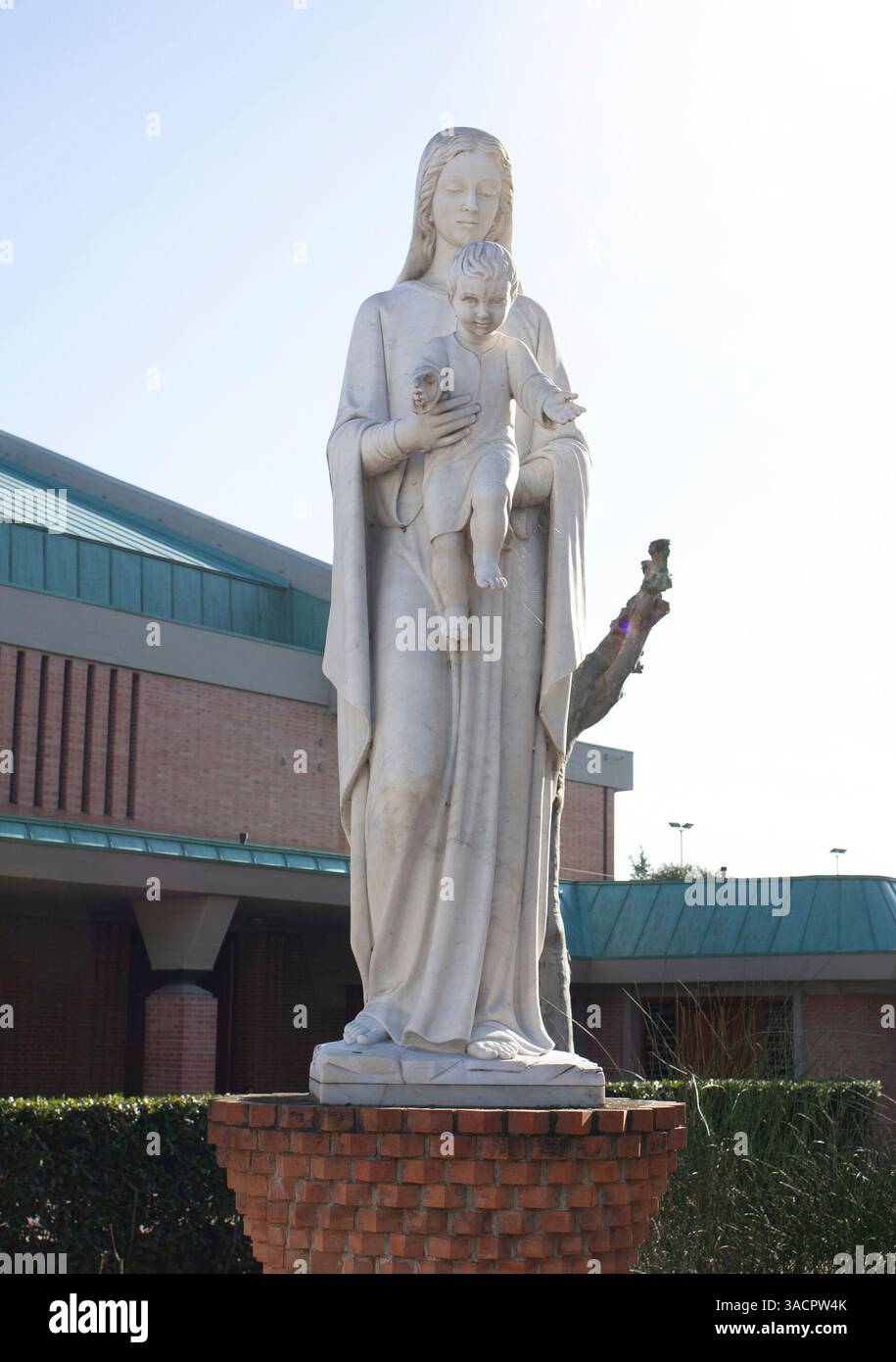 Statua in marmo bianco raffigurante la Madonna con Gesù bambino tra le braccia, posizionata di fronte a un moderno edificio della chiesa Foto Stock