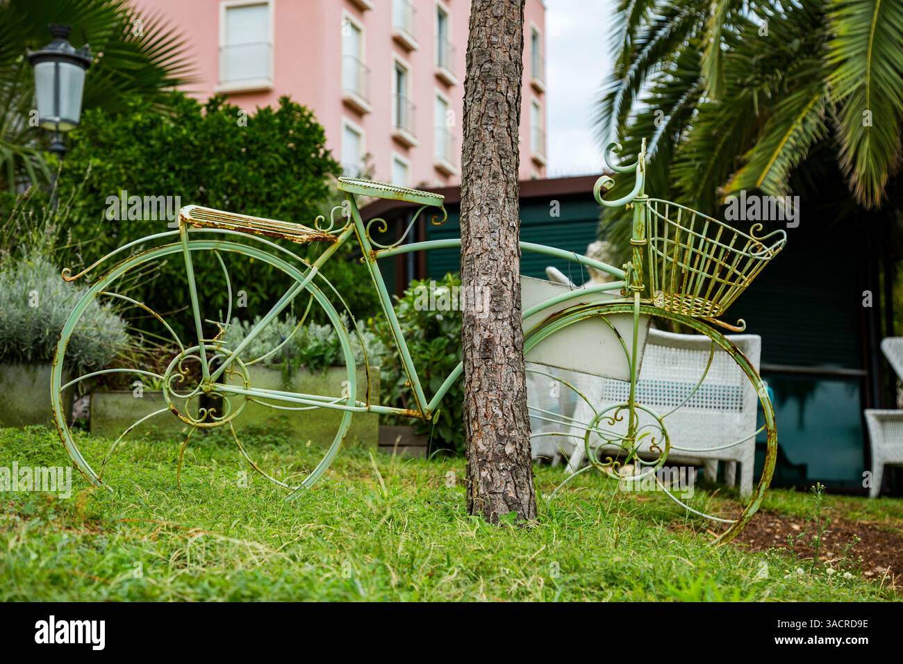 Una bicicletta verde come oggetto decorativo in un giardino frontale Foto Stock