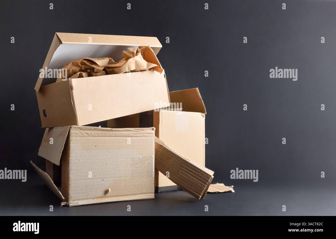 Concetto di inquinamento e riciclaggio di carta e cartone con pile di scatole di cartone su base nera isolata su sfondo nero. Vista frontale. Foto Stock