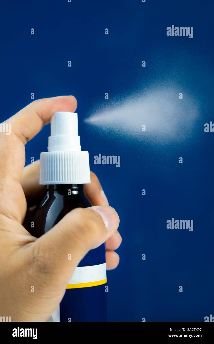 Modello di flacone spray per la crescita dei capelli con effetto nebulizzato, isolato su sfondo blu. Ideale per le vetrine dei prodotti. Foto Stock