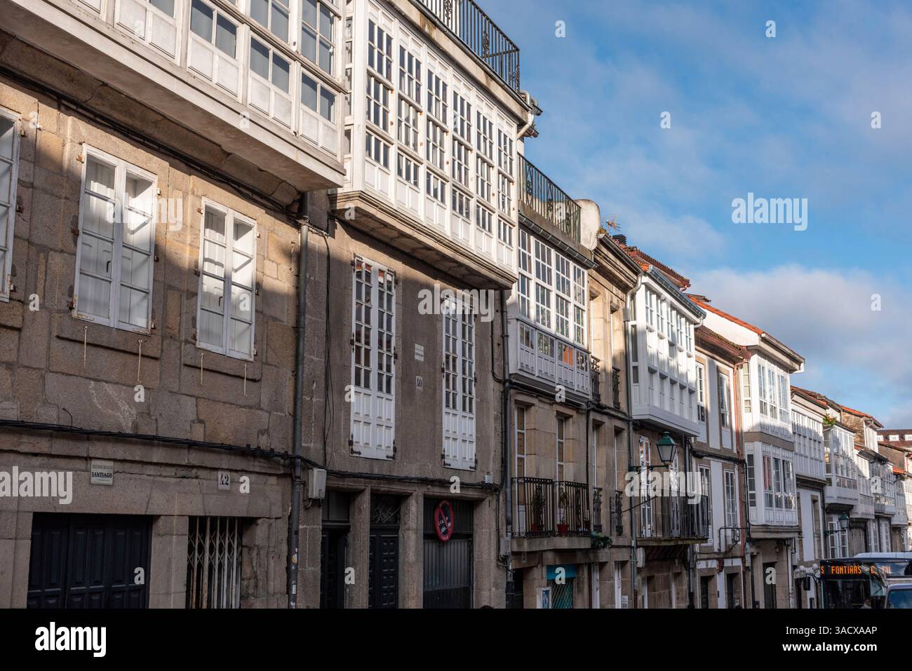 Affascinante via San Pedro con storiche case spagnole con edifici in pietra e balconi tradizionali sotto un cielo blu, Santiago de Compostella nel nord della Spagna Foto Stock