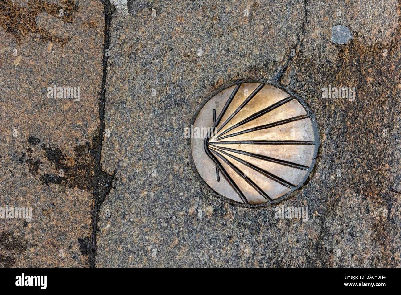 Conchiglia di pellegrinaggio in bronzo incastonata in un percorso in pietra che segna il cammino di Santiago, simboleggia il viaggio e la spiritualità, la Galizia nel nord della Spagna Foto Stock