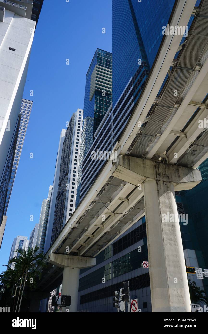 Immagine verticale e inclinata verso l'alto dei binari del treno pubblico Miami Metromover che passa attraverso i grattacieli del centro di Miami e Brickell Foto Stock