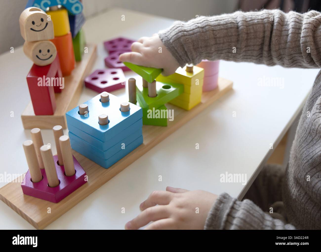 Bambino che gioca a un divertente gioco di logica con blocchi di legno colorati. Gioco di logica. Giochi educativi per bambini e sviluppo precedente. Foto Stock