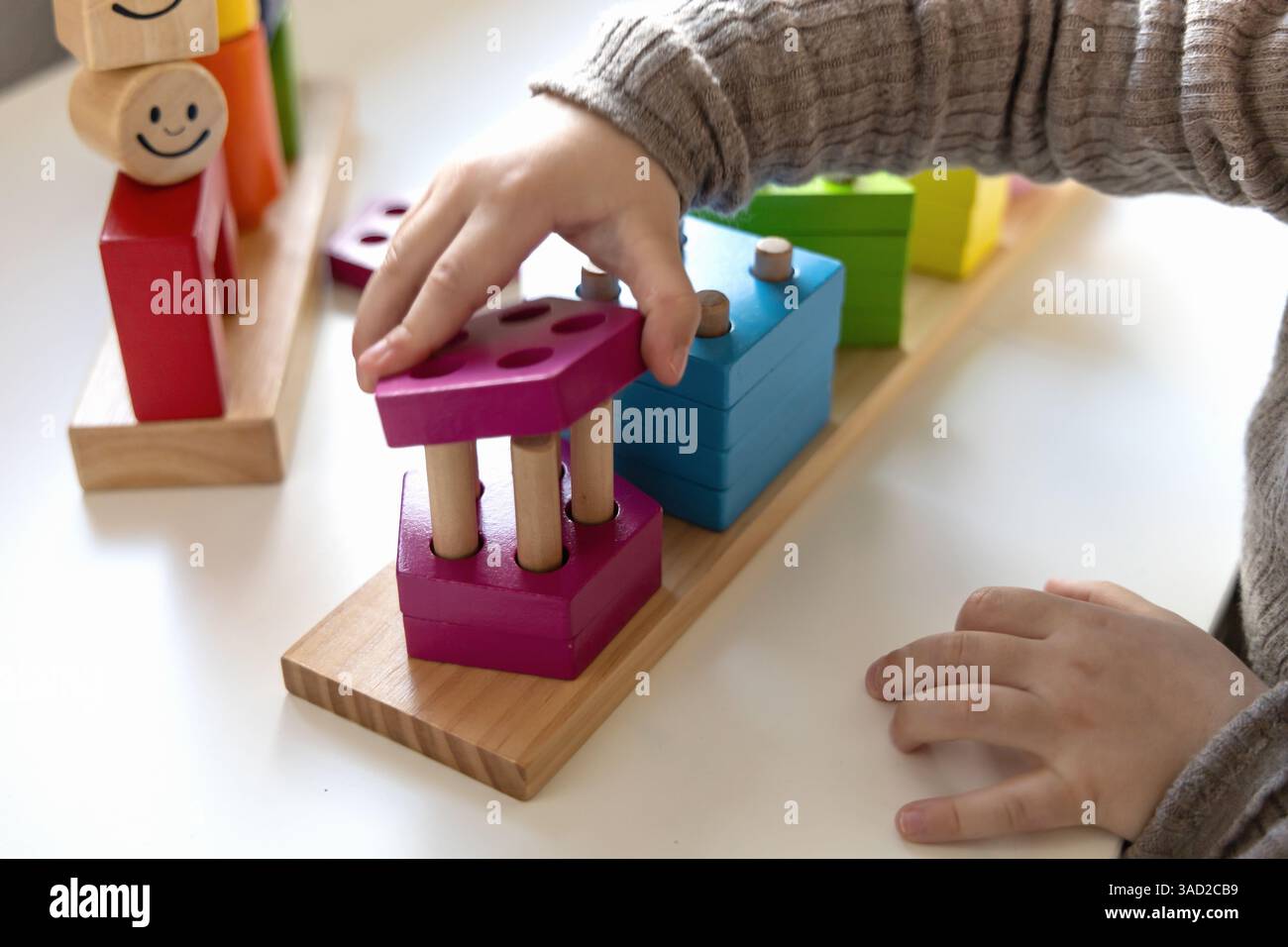Bambino che gioca a un divertente gioco di logica con blocchi di legno colorati. Gioco di logica. Giochi educativi per bambini e sviluppo precedente. Foto Stock