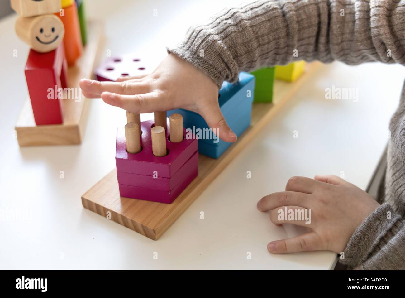 Bambino che gioca a un divertente gioco di logica con blocchi di legno colorati. Gioco di logica. Giochi educativi per bambini e sviluppo precedente. Foto Stock