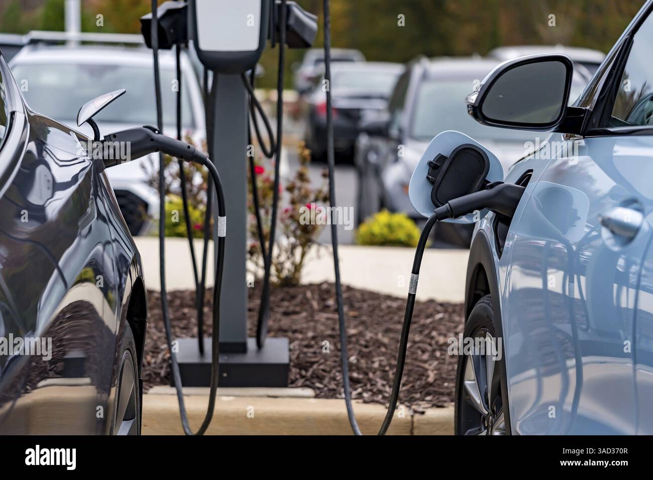 Un veicolo elettrico si ricarica in una stazione mentre il proprietario è al lavoro, consentendo una batteria completamente carica al momento del ritorno. Questa configurazione massima Foto Stock