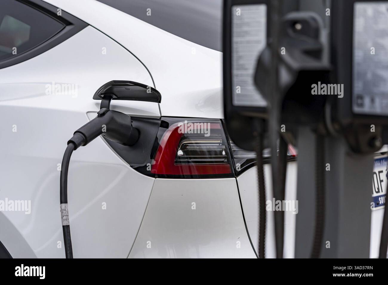 Un veicolo elettrico si ricarica in una stazione mentre il proprietario è al lavoro, consentendo una batteria completamente carica al momento del ritorno. Questa configurazione massima Foto Stock