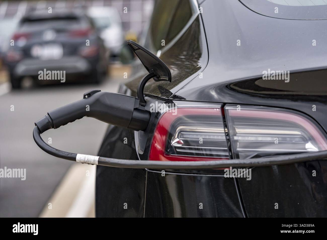 Un veicolo elettrico si ricarica in una stazione mentre il proprietario è al lavoro, consentendo una batteria completamente carica al momento del ritorno. Questa configurazione massima Foto Stock
