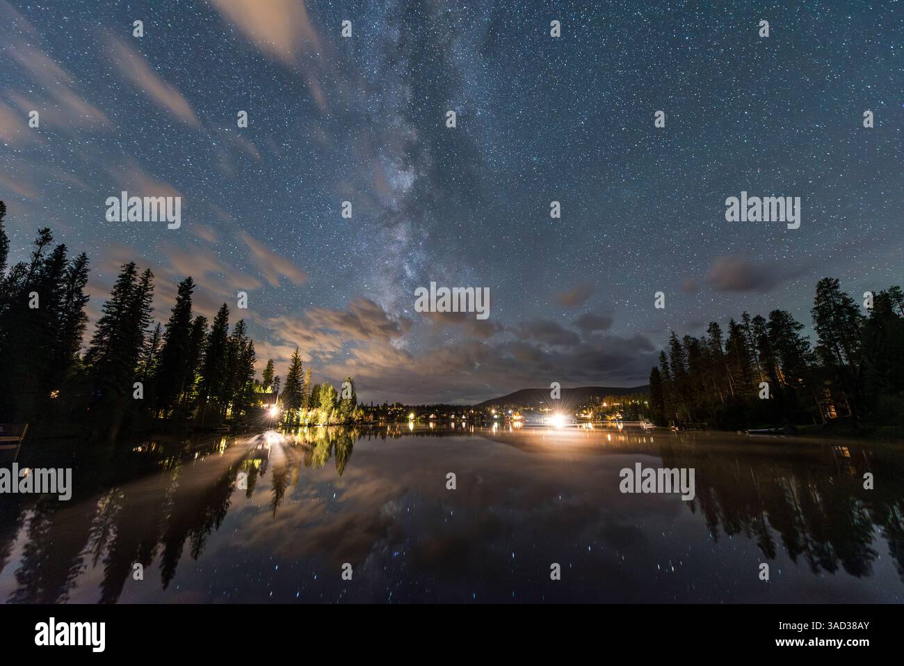 Cielo stellato notturno sul lago con riflessi e alberi circostanti Foto Stock