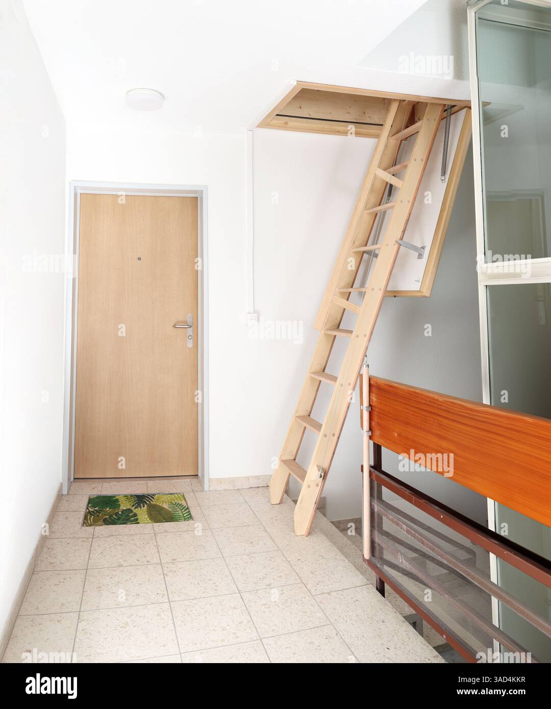 Scala mansardata o scala attico nella scala dell'edificio. Scala scorrevole loft con portello aperto o porta attico. Utilizzato per accedere a un loft, a un vano portaoggetti o a un attico Foto Stock