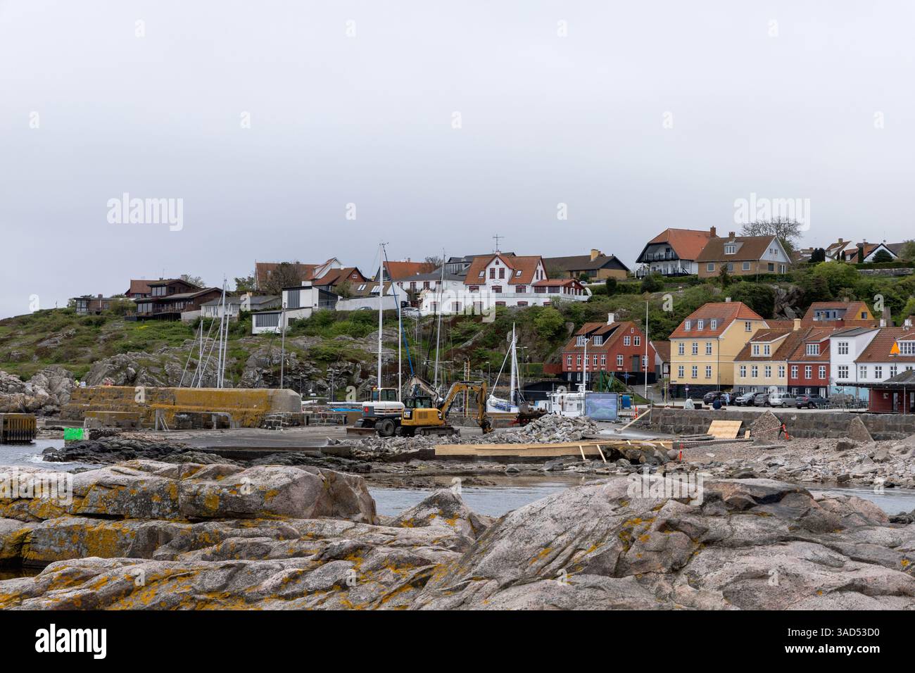 Costa rocciosa e una piccola città in lontananza con il tempo nuvoloso. Bellissimo paesaggio. Bornholm, Danimarca - 4 dicembre 2024 Foto Stock