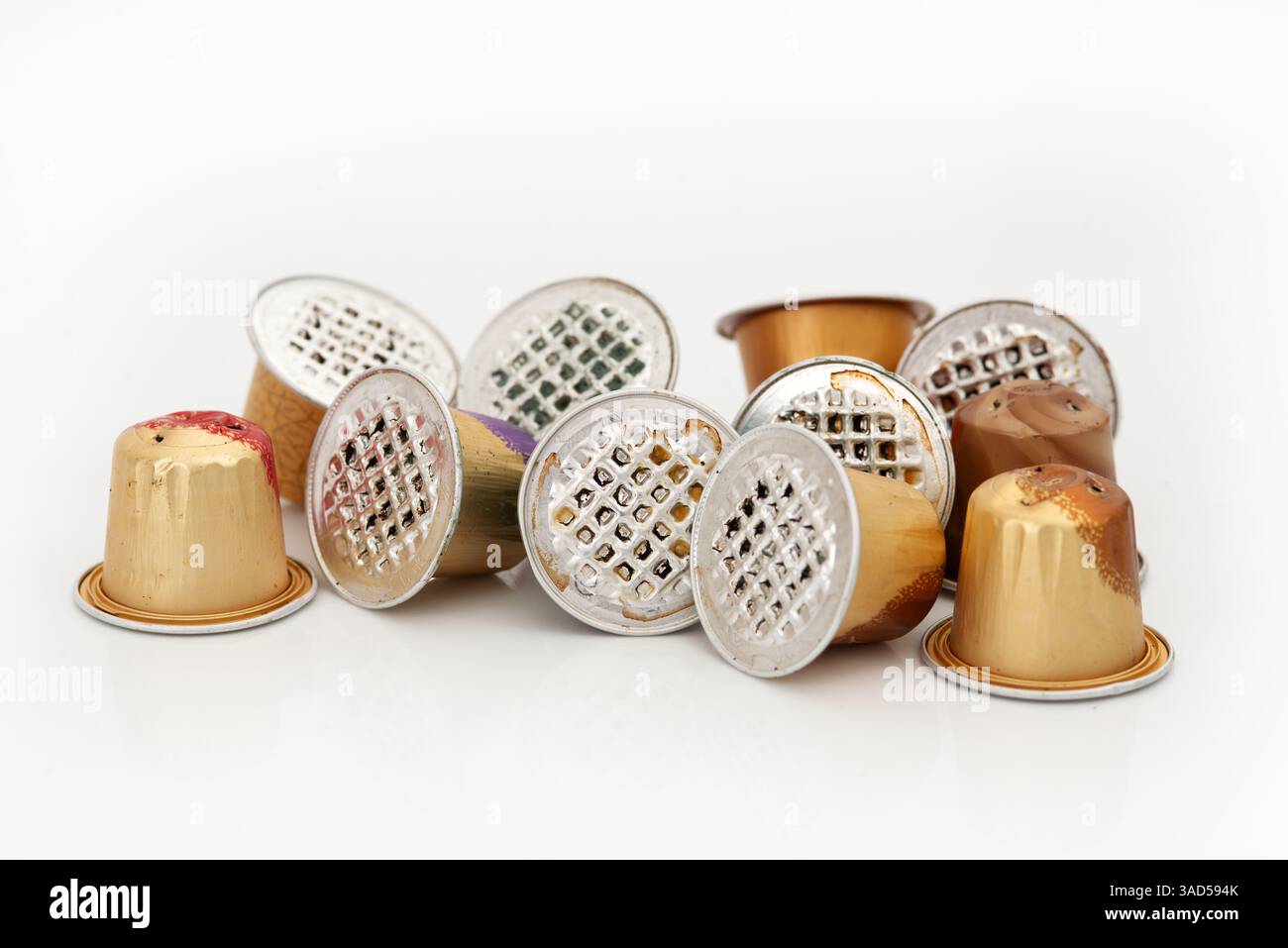 Capsule di caffè usate in vari colori metallici sparse su sfondo bianco Foto Stock