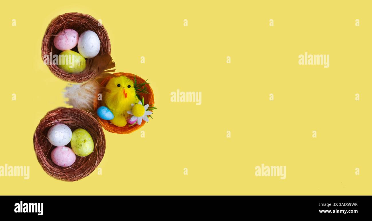Ci sono un sacco di uova di Pasqua e un pollo giocattolo nei nidi su sfondo giallo. Concetto di Pasqua, primo piano. Foto Stock