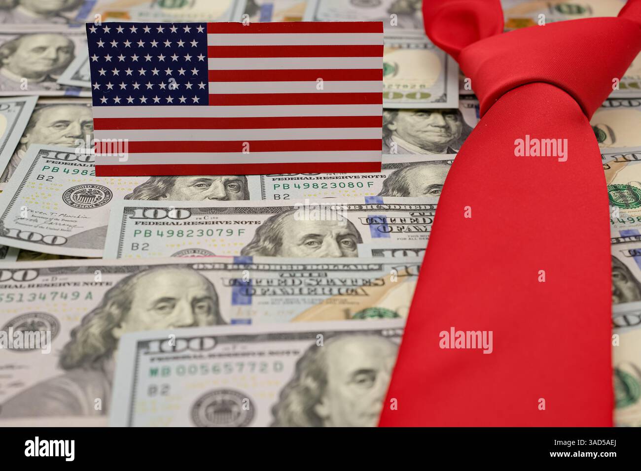 Bandiera americana con noi dollari. Cravatta rossa. Politica commerciale americana. Regime tariffario. Sfondo sfocato. Profondità di campo ridotta. Copia spazio. Foto Stock