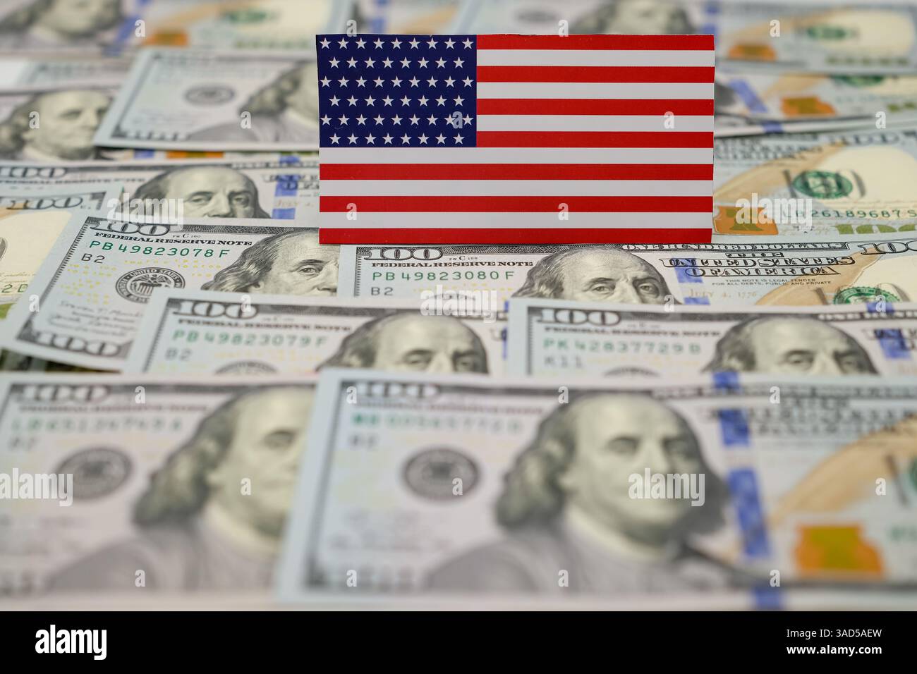 Bandiera americana con noi dollari. Politica commerciale americana. Regime tariffario. Sfondo sfocato. Profondità di campo ridotta. Copia spazio. Foto Stock