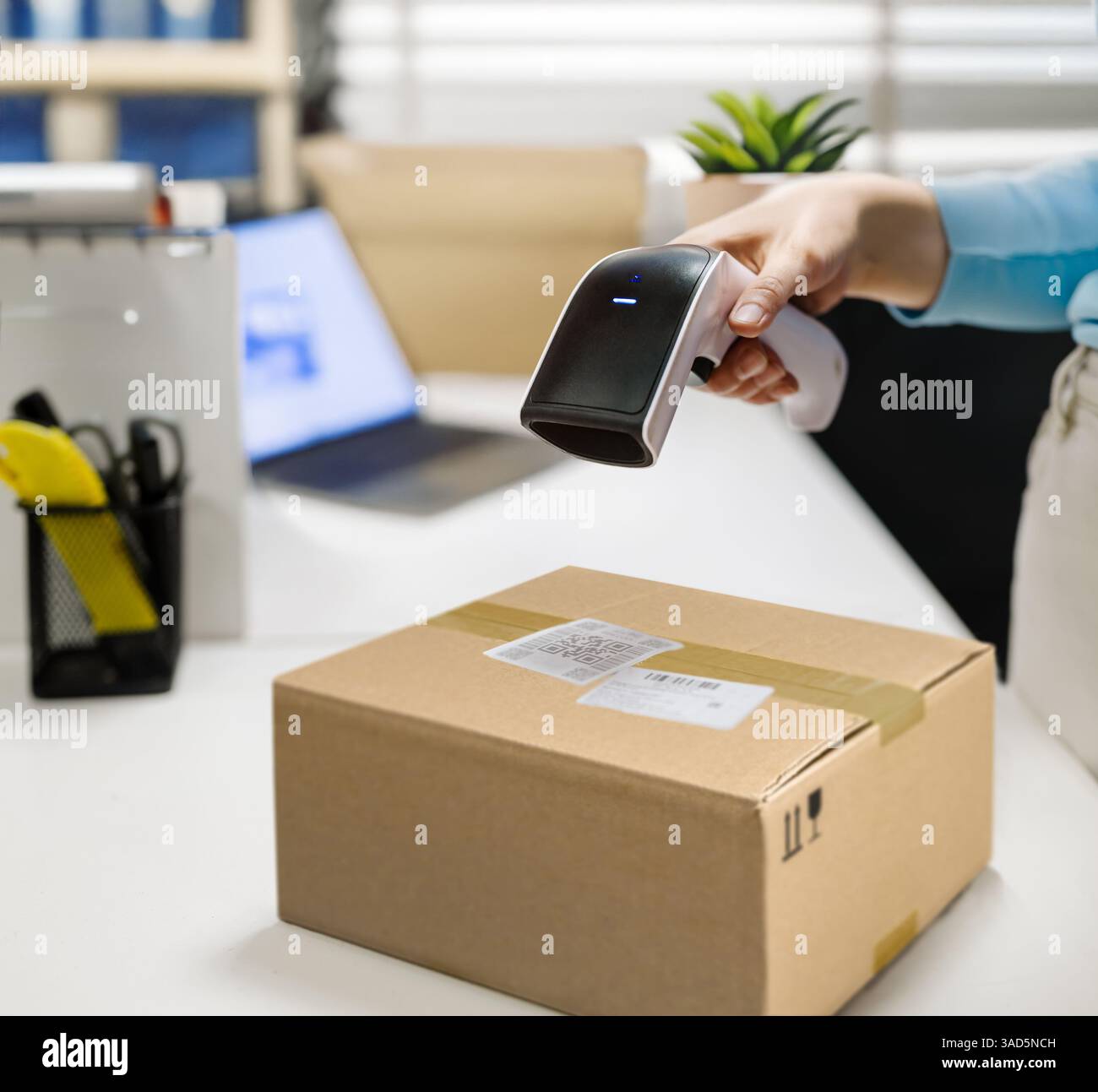 Moderno spazio di lavoro del punto di ritiro degli ordini online. Il dipendente sta eseguendo la scansione del codice QR del pacchetto A. Foto Stock