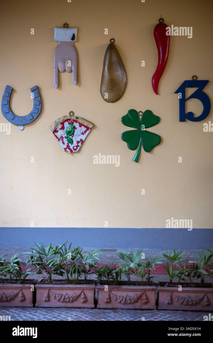 Collezione di fascino italiano della fortuna su un muro di Torino, con simboli tradizionali come un ferro di cavallo, un corno e un trifoglio a quattro foglie. Superstizioso Foto Stock