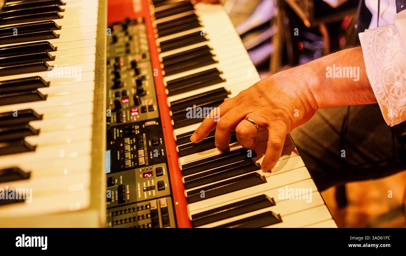 Vista ravvicinata della mano di un musicista che suona sapientemente i tasti di una tastiera, producendo melodie accattivanti in uno studio professionale Foto Stock