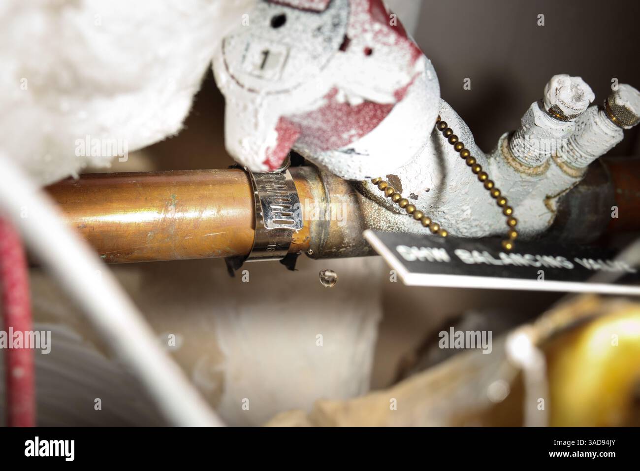 Fissaggio temporaneo del tubo dell'acqua nel soffitto con un morsetto in acciaio. Gocciolamento di acqua. Concetto di servizio idraulico o tuttofare fai da te. Noto anche come driv. A vite senza fine Foto Stock