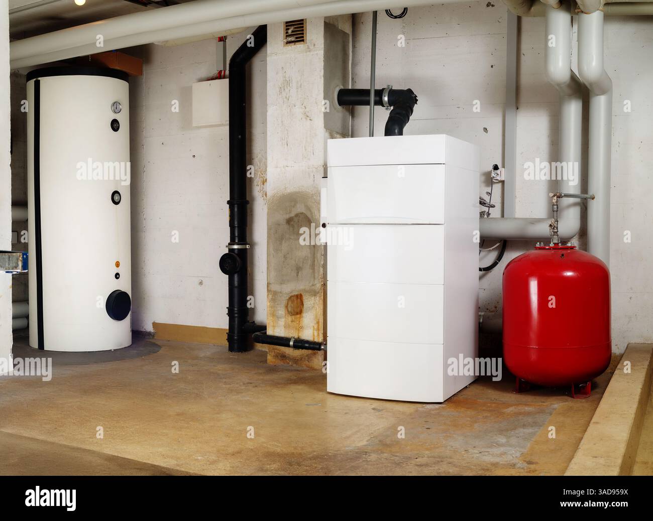 Impianto di riscaldamento e serbatoio dell'acqua calda in un edificio residenziale. Riscaldatore dell'acqua in acciaio e caldaia a condensazione dell'olio con serbatoio di espansione nel locale caldaia o nel seminterrato Foto Stock