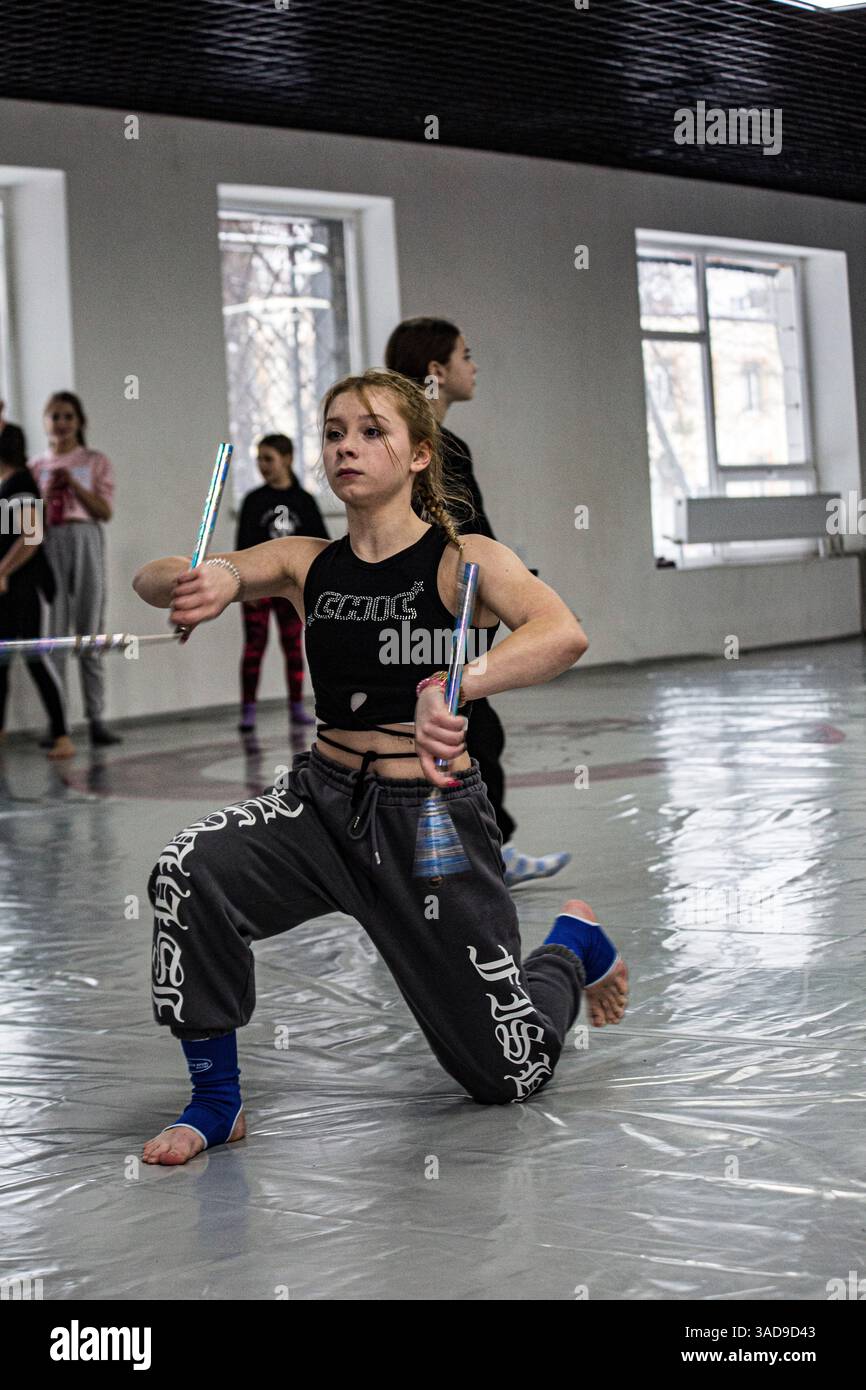 Giovane donna nella palestra WAKO Kickboxing esegue complessi con i nunchucks, sta superando il test WAKO nella palestra Pavel Zamyatin a Obolon a Kiev, Ucraina. Foto Stock