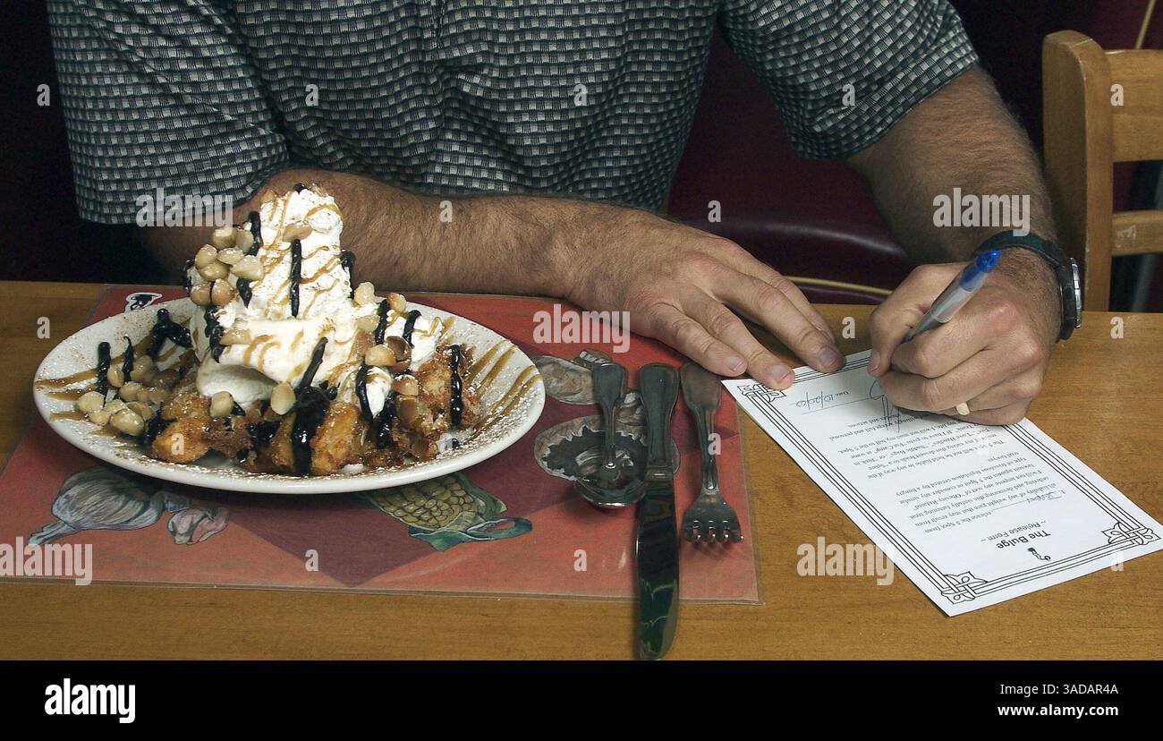 22 ottobre 2003; Seattle, Washington, Stati Uniti; il proprietario JEREMY HARDY al The 5 Spot, un ristorante di Seattle, firma un modulo di rinuncia prima di mangiare The Bulge - un delizioso mix di banane fritte zuccherate, gelati, noci di macadamia, panna montata e due tipi di sciroppo. I commensali che ordinano l'Ardenne devono firmare una rinuncia promettendo di non intentare una "causa per l'obesità" se ottengono un mento in più. La rinuncia è in parte una trovata pubblicitaria, in parte una dichiarazione politica rivolta direttamente agli avvocati che portano "tute grasse" contro i ristoranti fast-food, tra cui McDonald's... (Immagine di credito: Larry Davis/ZUMAPRESS.com) Foto Stock