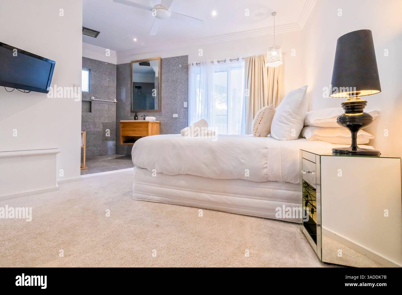 Interni lussuosi in stile di vita di una camera con letto queen size e bagno privato nella città australiana del lago Macquarie. Foto Stock