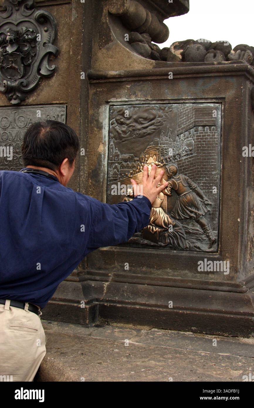 10 giu 2004; Praga, Repubblica Ceca; toccando i pannelli in fondo al saté di San Giovanni di Nepomuk sul Ponte Carlo si suppone che porti fortuna. Il destino non troppo fortunato di San Giovanni doveva essere torturato a morte e il suo corpo gettato da questo ponte nel 1393 per essersi rifiutato di divulgare la confessione della regina. (Immagine di credito: Kayte Deioma/ZUMAPRESS.com) Foto Stock