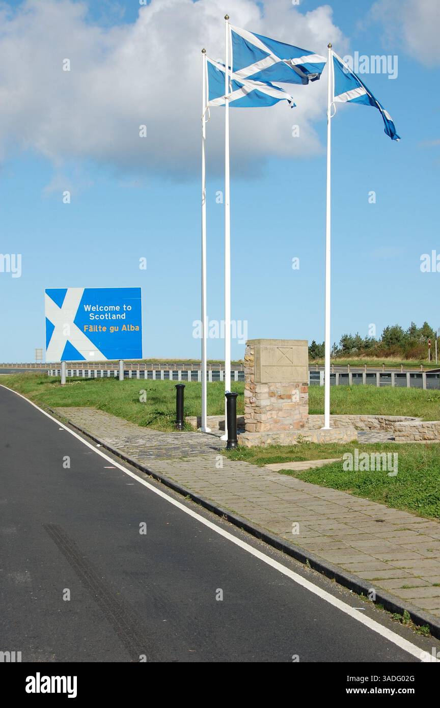 Il confine scozzese sulla A1 nel Northumberland è contrassegnato dai cartelli delle bandiere di Sant'Andrea e da una pietra segnaletica. Foto Stock