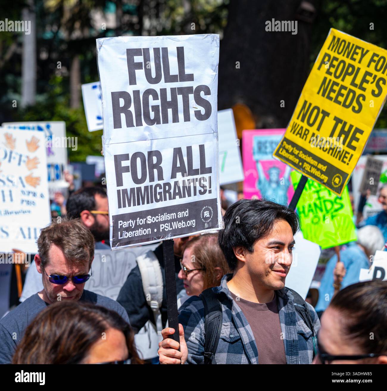 Un attivista detiene un cartello del partito del socialismo sugli immigrati che hanno pieni diritti alla protesta hands-off 50501, tenuta in centro sul Campidoglio. Foto Stock