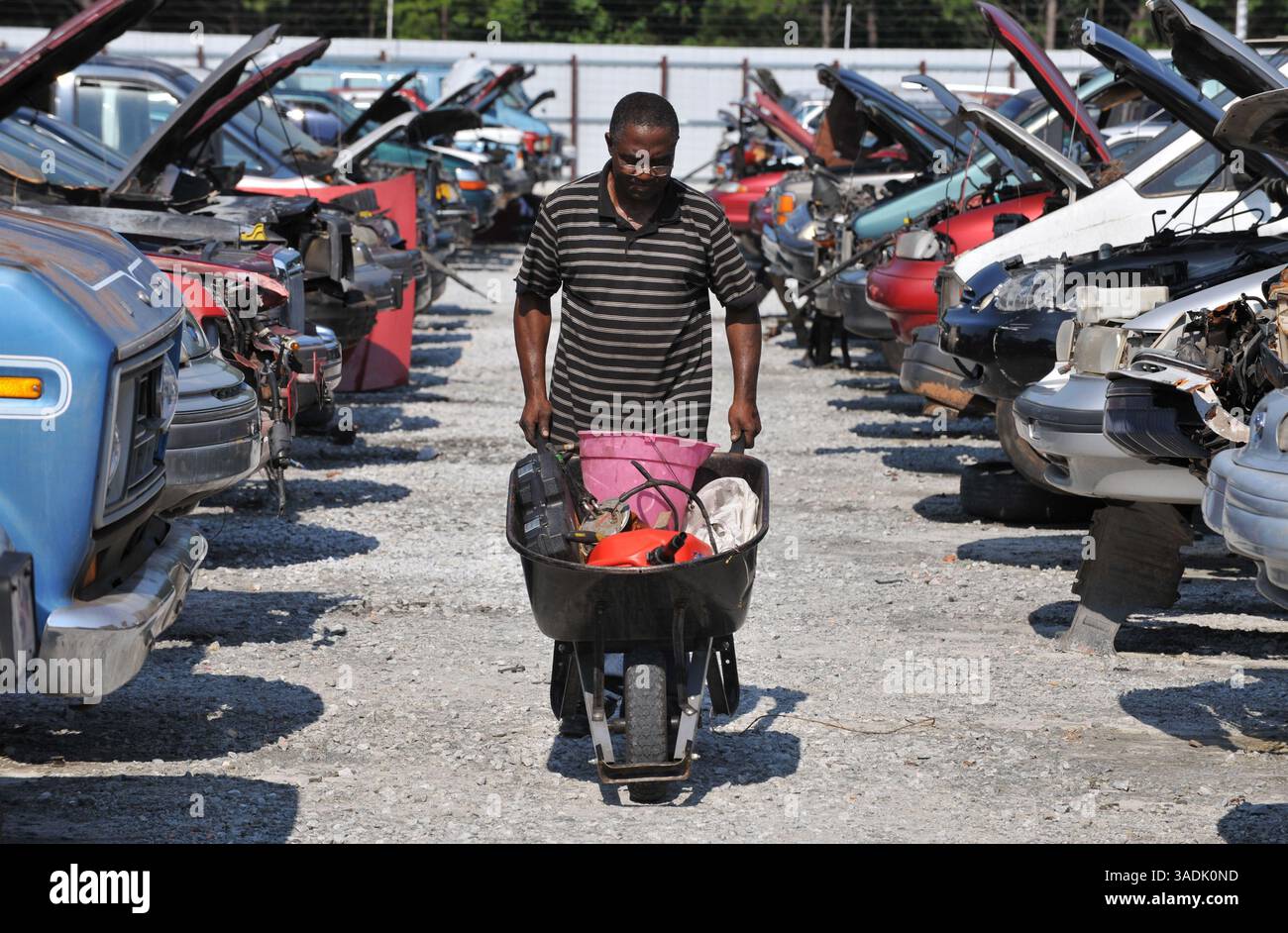 5 agosto 2009 - Lithonia, Georgia, Stati Uniti - il meccanico Allwell Osuala con una carriola piena di parti di una Ford Taurus presso il deposito ricambi auto Pull-A-Part. La catena di depositi di recupero "fai da te" è tra le centinaia di strutture approvate a livello nazionale per elaborare e riciclare i veicoli "Cash for Clunkers" dei concessionari (immagine di credito: Robin Nelson/ZUMAPRESS.com) Foto Stock