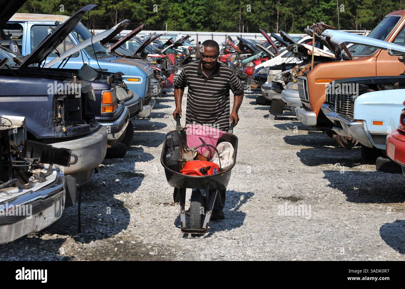 5 agosto 2009 - Lithonia, Georgia, Stati Uniti - il meccanico Allwell Osuala con una carriola piena di parti di una Ford Taurus presso il deposito ricambi auto Pull-A-Part. La catena di depositi di recupero "fai da te" è tra le centinaia di strutture approvate a livello nazionale per elaborare e riciclare i veicoli "Cash for Clunkers" dei concessionari (immagine di credito: Robin Nelson/ZUMAPRESS.com) Foto Stock