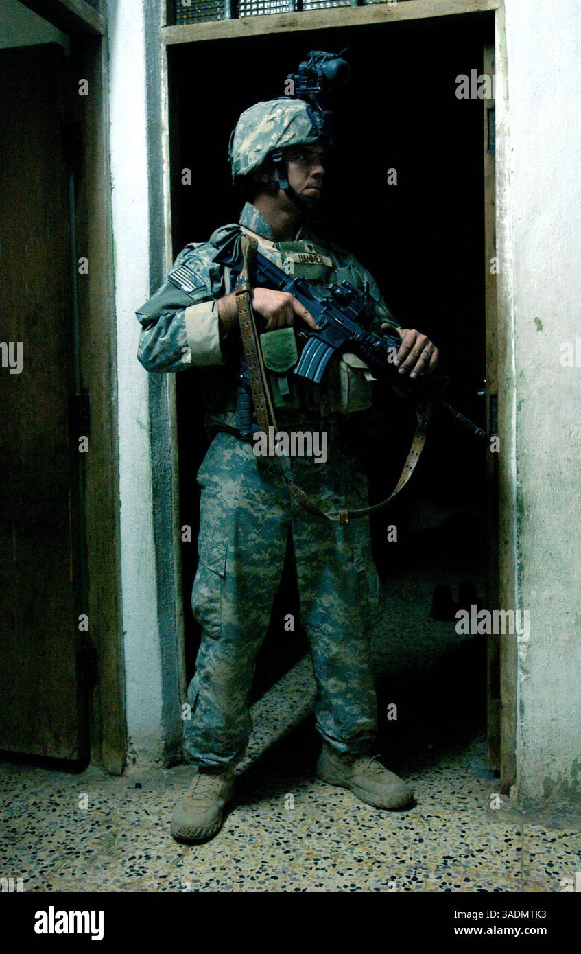 16 settembre 2005; Mosul, IRAQ; SPC. ERIC HAMMER è di guardia in una stanza piena di donne e bambini durante un raid a Mosul, Iraq, il 17 settembre 2005. La fanteria fa parte del 172nd Stryker Brigade Combat Team di Fort Wainwright, Alaska. (Immagine di credito: Bill Putnam/ZUMAPRESS.com) Foto Stock