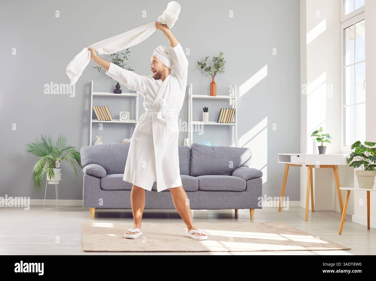 Uomo felice e divertente in un accappatoio e asciugamano bianco, che si rilassa e si diverte dopo la doccia Foto Stock