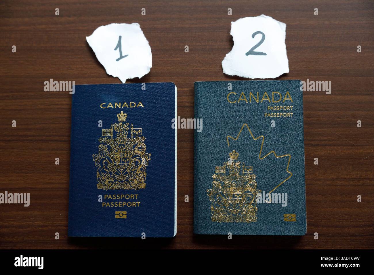 Vancouver, Canada - 18 marzo 2025: Due passaporti canadesi posizionati su una superficie in legno, che mostrano l'evoluzione del design Foto Stock