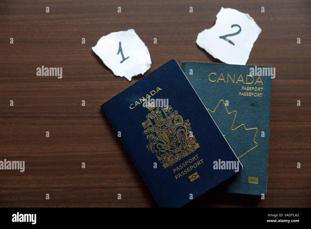Vancouver, Canada - 18 marzo 2025: Due passaporti canadesi posizionati su una superficie in legno, che mostrano l'evoluzione del design Foto Stock