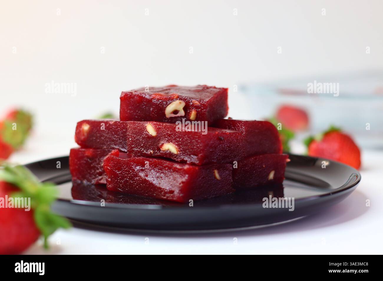 Halwa alle fragole, un dolce indiano con una ricca tonalità rosa. Servita in una ciotola tradizionale, ha una consistenza lucida e viene guarnita a pezzi Foto Stock