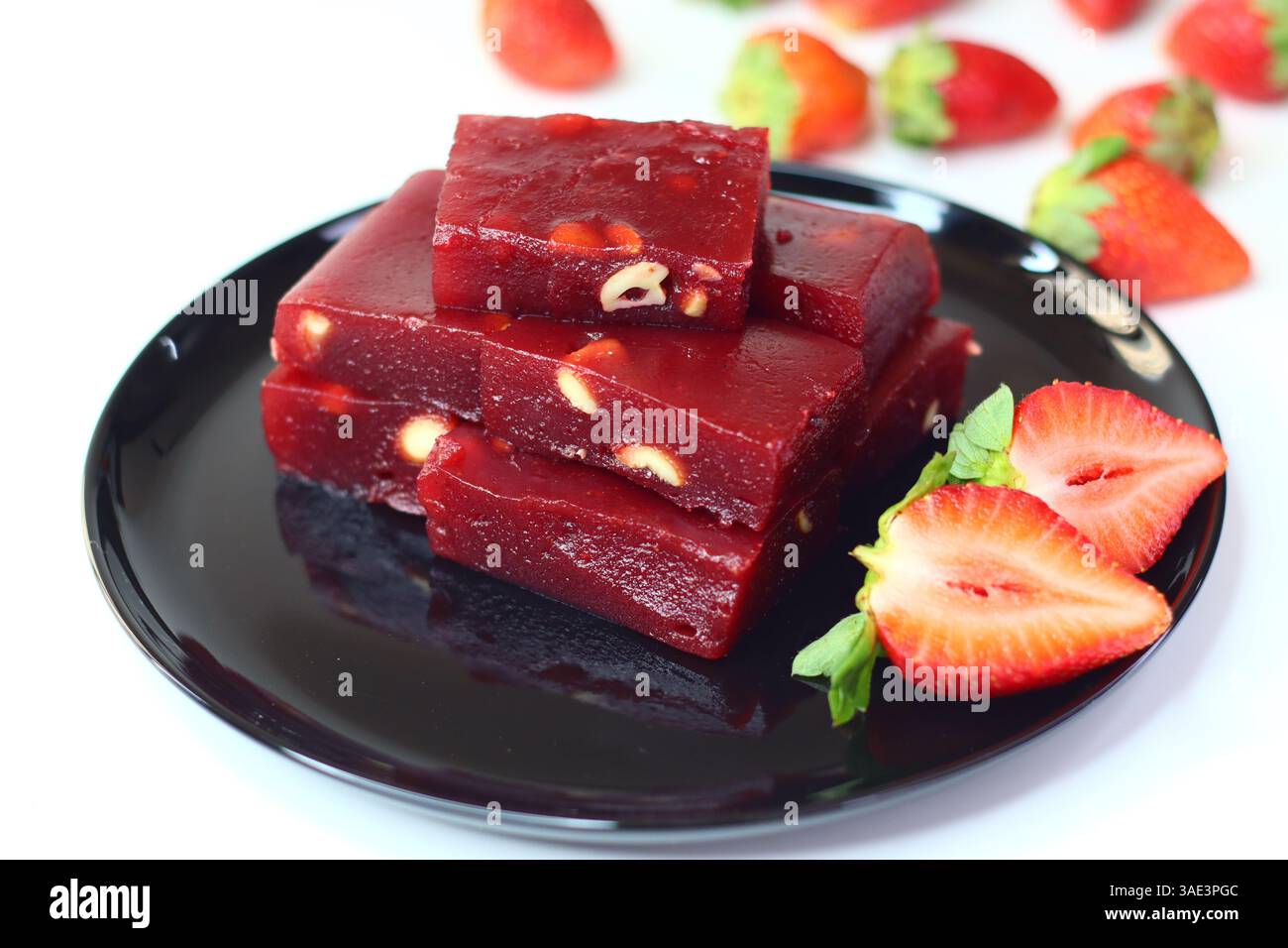 Halwa alle fragole, un dolce indiano con una ricca tonalità rosa. Servita in una ciotola tradizionale, ha una consistenza lucida e viene guarnita a pezzi Foto Stock