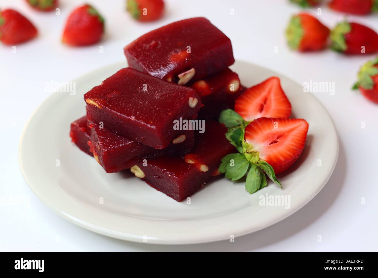 Halwa alle fragole, un dolce indiano con una ricca tonalità rosa. Servita in una ciotola tradizionale, ha una consistenza lucida e viene guarnita a pezzi Foto Stock