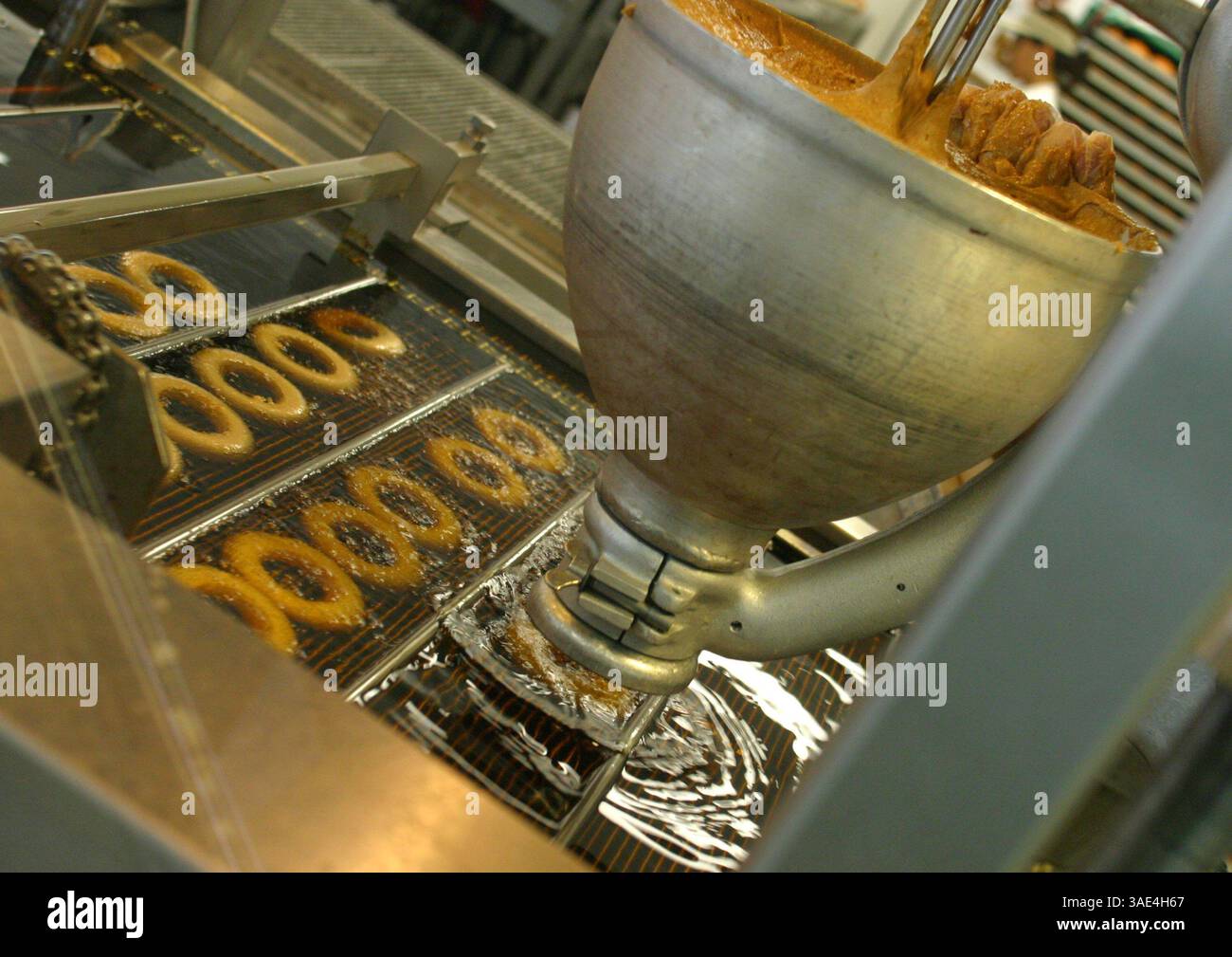 09 ottobre 2003; Laguna Niguel, CA, USA; le ciambelle Krispy Cream stanno conquistando il mondo e la gente sembra che non ne abbia abbastanza. Nella foto: La produzione di ciambelle fritte ricoperte di zucchero come si vede in ogni negozio Krispy Kream. Oggi hanno oltre 300 negozi in tutto il mondo. (Immagine di credito: Ruaridh Stewart/ZUMAPRESS.com) Foto Stock
