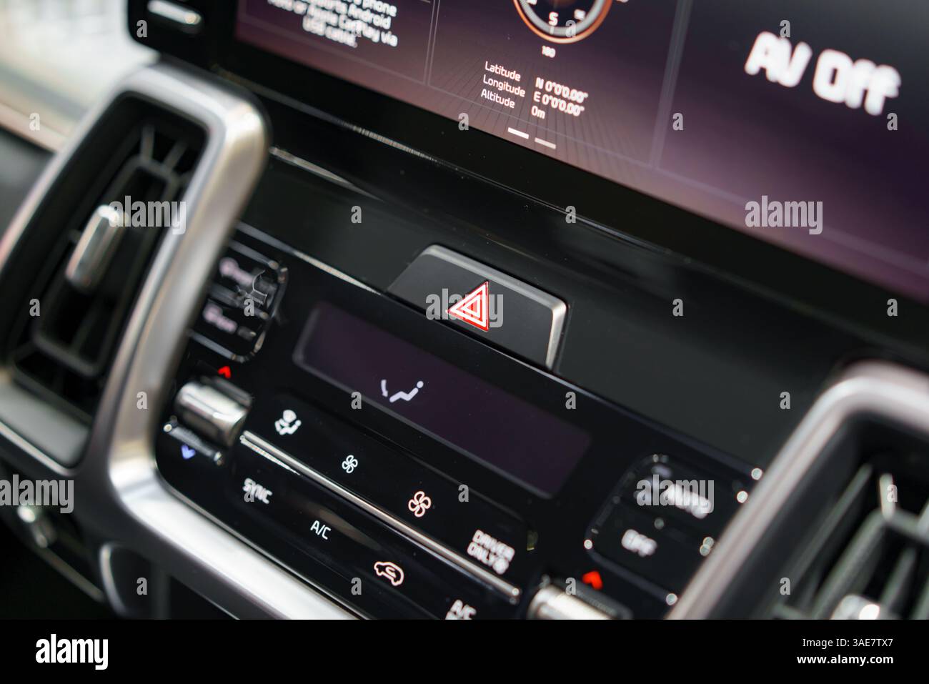 uno sguardo dettagliato sul cruscotto di un veicolo moderno, dotato di display di informazione e intrattenimento con touch screen, pulsante luci di emergenza e comandi della climatizzazione per migliorare la capacità di comando del conducente Foto Stock