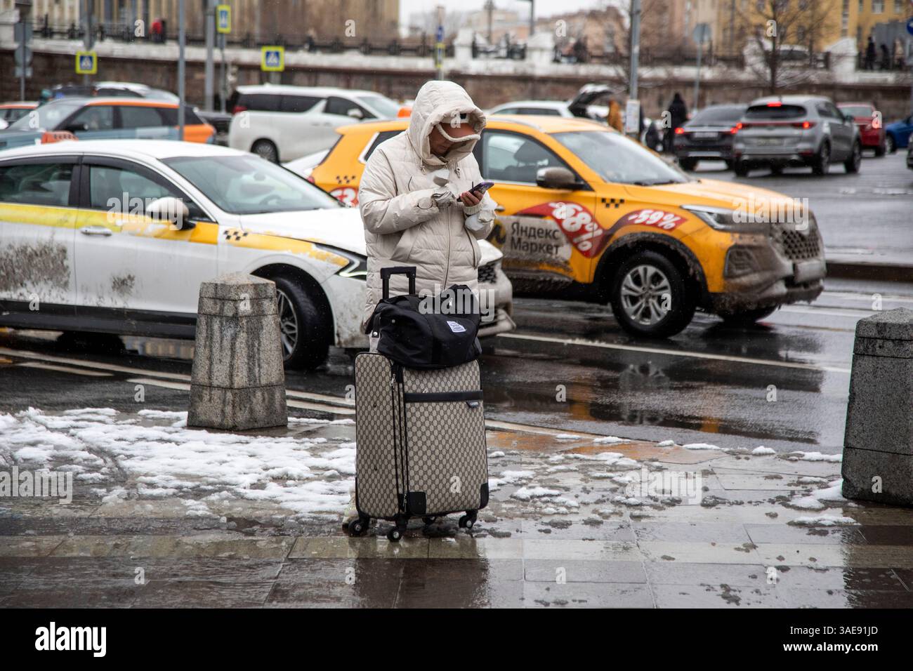 Mosca, Russia. 6 aprile 2025. Una donna chiama un taxi attraverso un'applicazione mobile nella piazza vicino alla stazione ferroviaria Belorussky nel centro di Mosca, in Russia Foto Stock