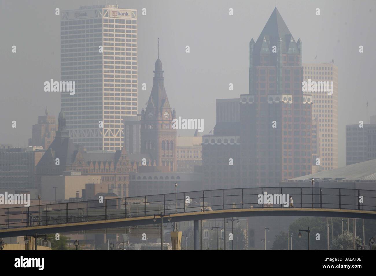 13 settembre 2011 - Milwaukee, WISCONSIN, Stati Uniti - Un pedone attraversa un ponte pedonale con uno skyline nebuloso di Milwaukee sullo sfondo, 13 settembre 2011. Un enorme incendio boschivo nella Boundary Waters Canoe area in Minnesota ha mandato cenere e fumo in gran parte del Wisconsin, compresa la metropolitana di Milwaukee. (Immagine di credito: © Mike De Sisti/Milwaukee Journal Sentinel/MCT/ZUMAPRESS.com) Foto Stock